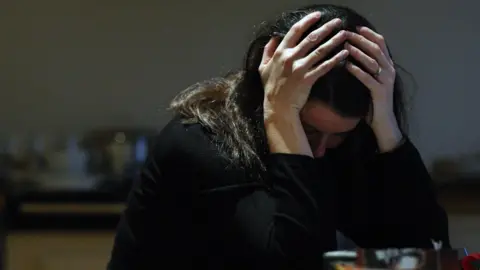 PA Media Woman holding head