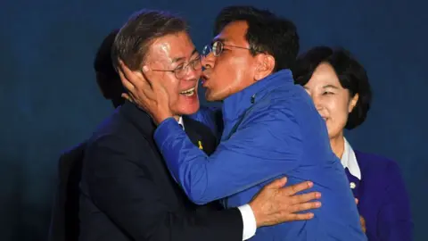 Getty Images South Korean presidential candidate Moon Jae-in (L) of the Democratic Party receives a kiss from his party member Ahn Hee-Jung (R)