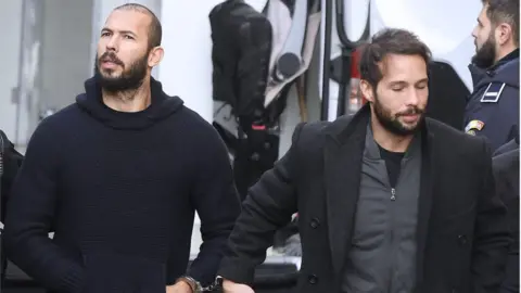 Getty Images Andrew Tate (left) and his brother Tristan (right) leaving court in Bucharest