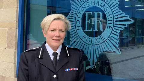 Nottinghamshire PCC Woman with light-coloured hair in a police uniform standing outside a police HQ building