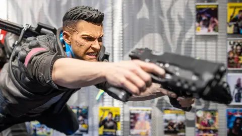 Getty Images A statue of Cyberpunk's main player character leaps through the air, wielding a high-tech gun and his cybernetic augments clearly visible on his face
