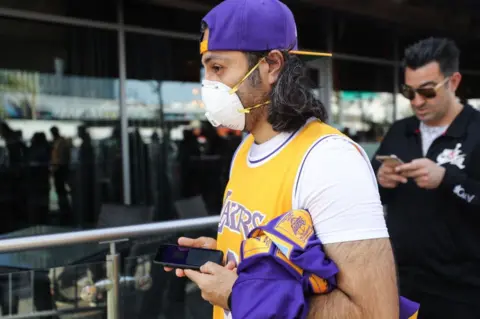 Getty Images A Kobe Bryant fan wears a mask to his memorial service in LA on Monday