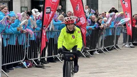 Mollie King cycles into Queen Victoria Square