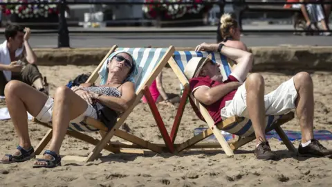 PA Media People sunbathe on Scarborough beach