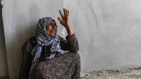 AFP A member of the Sheikh Wais family reacts as she asks Kurdish fighters to recover the bodies of her relatives from under the rubble of a building in western Raqqa on 12 July 2017