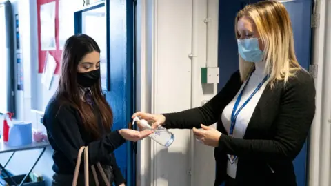 Getty Images Teacher squirts hand sanitiser onto a pupil's hand