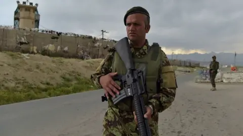 AFP via Getty Images Afghan National Army (ANA) soldiers stand guard at a checkpoint outside a US military base in Bagram in April 2021