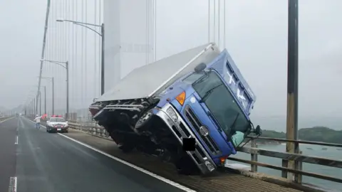 AFP PHOTO / Kagawa prefectural police Truck blown over on the Seto Ohashi bridge in Sakade