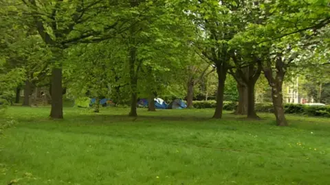 tents in a park showing people sleeping rough