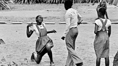 Sunmi Smart-Cole A photo by Sunmi Smart-Cole entitled: "Teacher Brutality" - 1984, showing a student being flogged in Nigeria