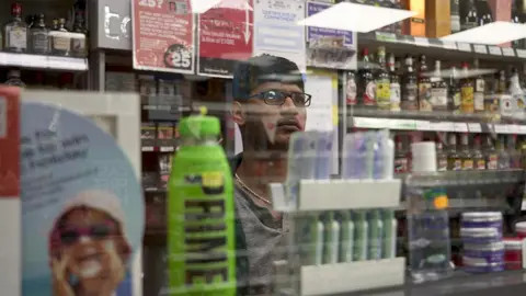 Shopkeeper behind glass screen