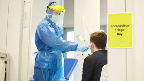 Getty Images Healthcare worker takes boys temperature