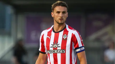 Taylor Harwood-Bellis in action for Southampton wearing a red and white shirt