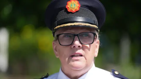 PA Media A close-up image of Assistant Commissioner Paula Hilman. Her mouth is open as she speaks. She is wearing a black police hat, a pair of dark-rimmed square glasses, and has her blonde hair tied back.