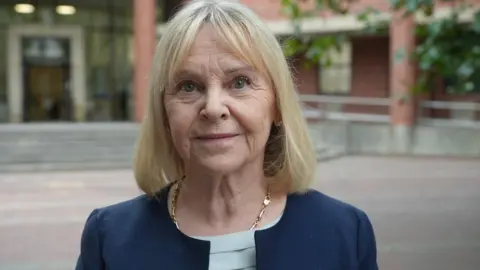 Sue Lockwood, pictured outside Hull Crown Court. She has blonde shoulder-length hair and is wearing a blue jacket with a brooch on the lapel.