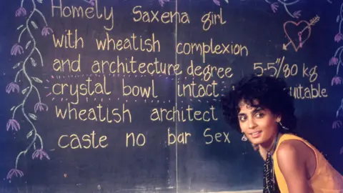 The Film Heritage Foundation A young Arundhati Roy wearing a yellow tunic and a black scarf bends slightly in front of a blackboard in a scene from In Which Annie Gives It Those Ones
