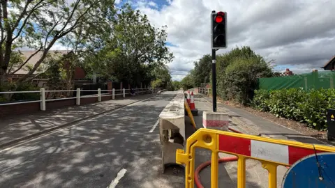 Temporary traffic lights and a barrier blocking half of the road in Ansty, Warwickshire.