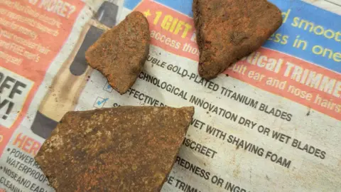 Carenza Lewis A view of three sherds found in a garden in Newtown Linford near a river. They are covered in mud.