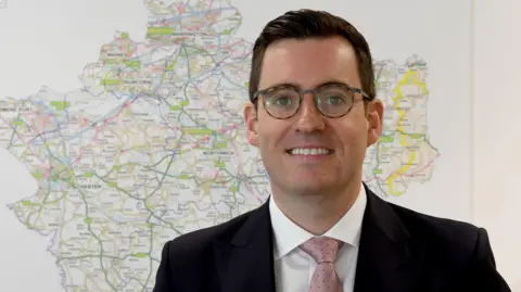 PCC Dan Price in front of a map of Cheshire