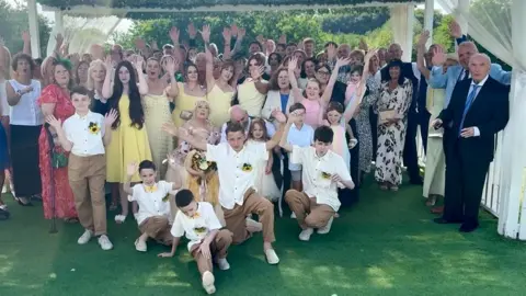 FlashBack Photography The wedding guests all standing together, waving at the camera