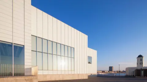 The image shows the outside of an art gallery against a deep blue sky.