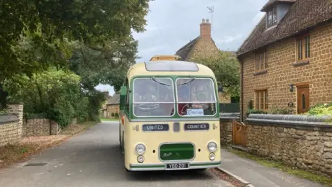 Green and white single-decker bus in a picturesque village