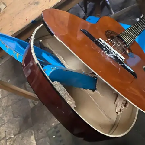 Youth Vision A guitar is smashed open.