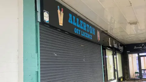 A shuttered shop in a parade of other shops