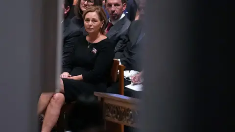Getty Images Graham's sister, Darline Graham, has been appointed to fill his South Carolina US Senate seat. She wears a black dress as she sits in the front row of pews.