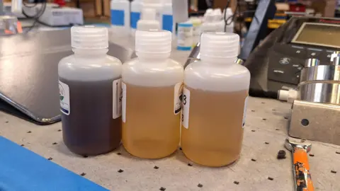 Aquagga Three bottles showing samples of untreated and treated PFAS-rich liquid.