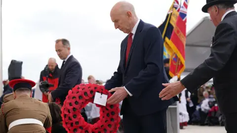 PA Media John Healey sets down a wreath in France