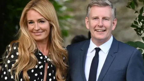Getty Images Cat Deeley and Patrick Kielty pose in front of a flower arch. 