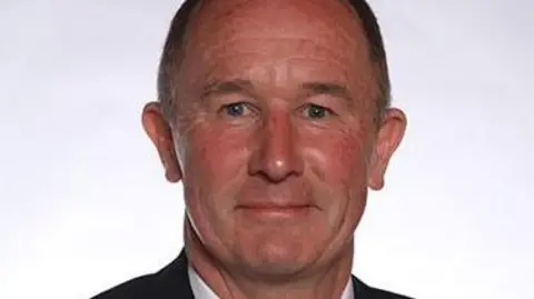 Stockton-on-Tees Borough Council Councillor Tony Riordan. He is a middle-aged man with short brown hair and wearing a suit.