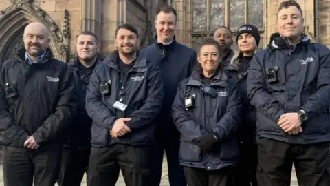 Rotherham Council A large group of men and women all dressed in black uniforms pose together in two rows