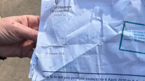 A hand holding a letter headed "HM Revenue & Customs" and dated 11 October 2020.