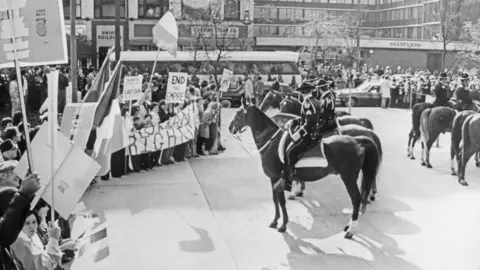 Getty Images Police on horses face off with protesters holding signs calling of the end of the British empire