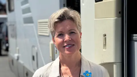 George King/BBC A head and shoulders shot of Katrina Cable. She is smiling and looking directly into the camera. She is wearing a cream shirt with a lace top beneath it. She is standing in front of her motorhome.