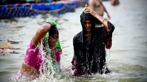 Ankit Srinivas Two women take a dip in the river at the Kumbh Mela