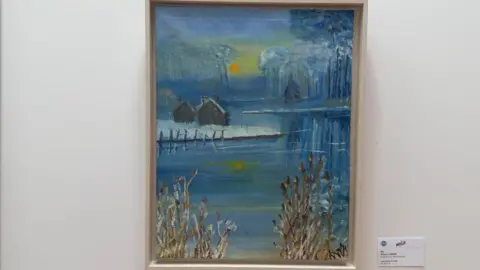 Framed painting of a tranquil scene of log cabins set around a lake