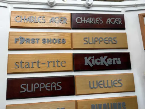 Wooden signs show the shop signage of Charles Ager as well as other shoe brands such as Kickers, Start-rite. Wellies and First Shoes