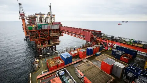 North Sea rig with industrial crates and ships in distance at sea on horizon