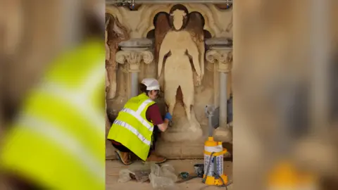 Cliveden Conservation' Someone chipping away at a human shaped stone sculpture at Wells Cathedral