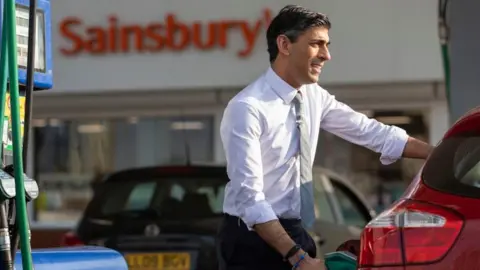 Simon Walker/ HM Treasury Prime Minister Rishi Sunak seen filling up a car at a petrol station