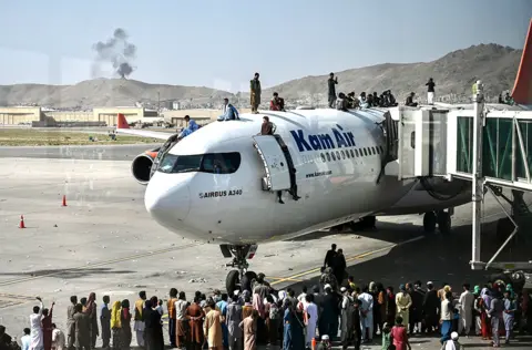 AFP Afghan people climb atop a plane as they wait at the Kabul airport on 16 August 2021