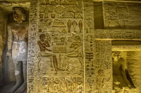 AFP/Getty Images A wall covered in engraved hieroglyphs, including people, weighing scales, birds and what appears to be food