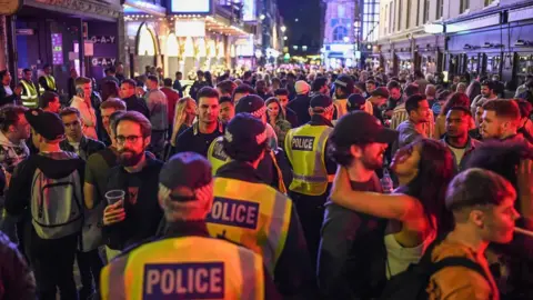 Getty Images Police officers are seen walking through heavy crowds in Soho, central London