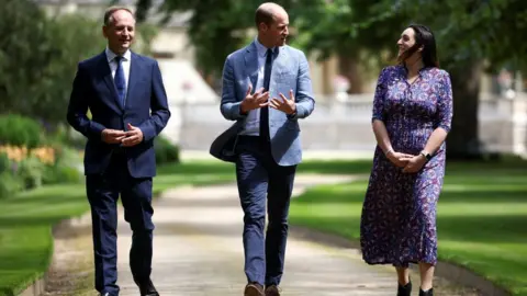 PA Media NHS England chief executive Sir Simon Stevens and NHS Charities Together chief executive Ellie Orton walk with Prince William