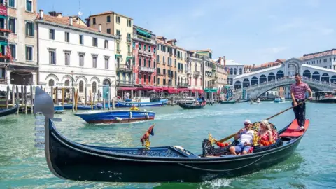 Tourists enjoy a gondola ride in Venice, Italy, in 2021