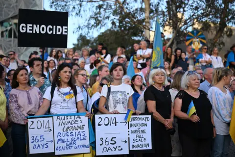 JAMES ROSS/EPA-EFE/REX/Shutterstock People gather during a candlelight vigil to commemorate the one-year anniversary of the war in Ukraine at Federation Square in Melbourne, Australia, 24 February 2023.