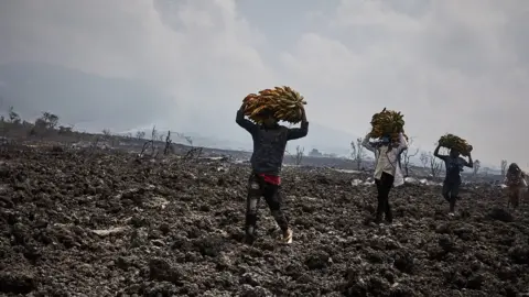 EPA Congolese communities walking across lava flows in Kibati, North of the city of Goma, in the aftermath of a volcanic eruption in North Kivu, Democratic Republic of Congo, 25 May 2021